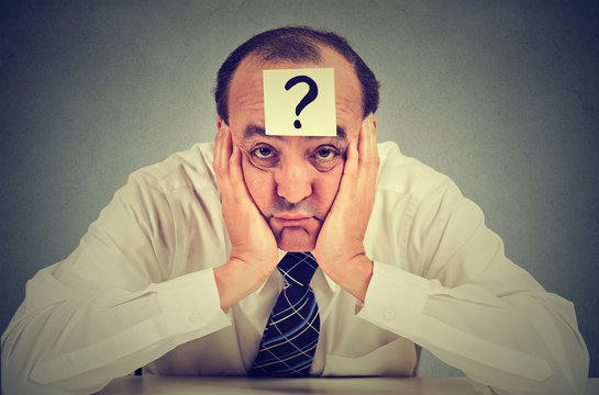 clueless business man with question mark sitting at table