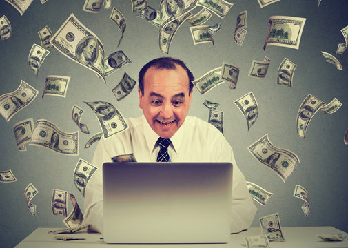 Man using laptop building online business making money dollar bills cash falling down. Money rain