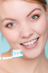 woman holds toothbrush with toothpaste cleaning teeth