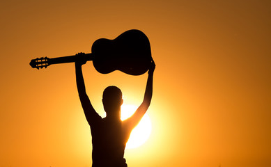 Silhouette of girl with raised guitar