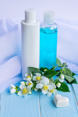 Lotion and tonic in bottles, flowers, white cloths, heart shaped soap and beads - using jasmine essence for cosmetic products concept