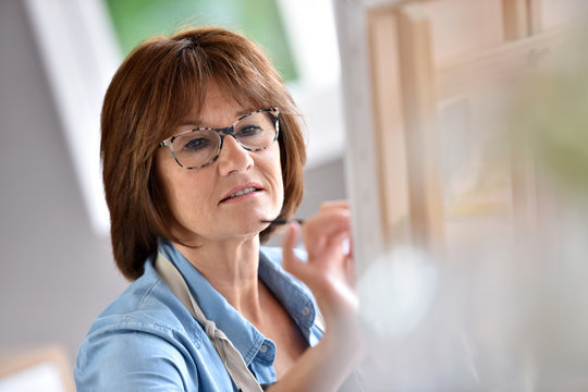 Senior woman painting on canvas