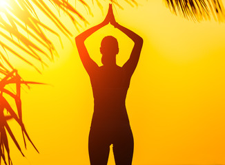 Silhouette of young woman practicing yoga
