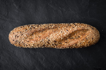 Bread with grains and seeds on the dark stone table top view