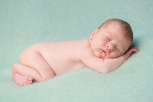 sweet naked newborn child sleeping on blanket