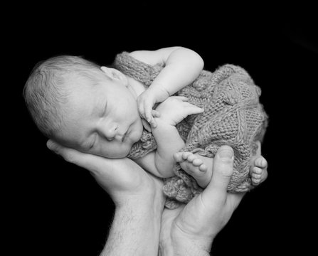 sweet sleeping newborn baby lifted up on hands black and white photo