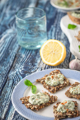 Crisp grain bread with tzatziki on the  blue ceramic plate vertical