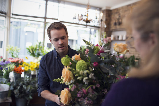 Florist Serving Male Customer With Roses In Shop