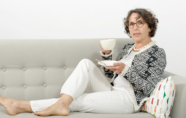 mature woman drinking tea on the sofa