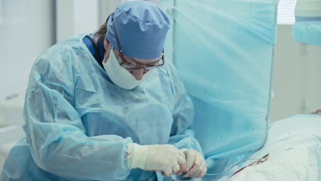 Experienced female surgeon performing coronary artery bypass surgery assisted by nurse in operating room, shot on Sony NEX 700 + Odyssey 7Q