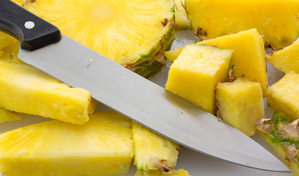 Slicing a fresh pineapple on a cutting board