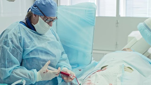 Mature female surgeon performing coronary artery bypass graft assisted by nurse, shot on Sony NEX 700 + Odyssey 7Q