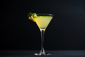 Gelber Martini-Cocktail mit Zitrone und Minze auf rustikalem Holzhintergrund