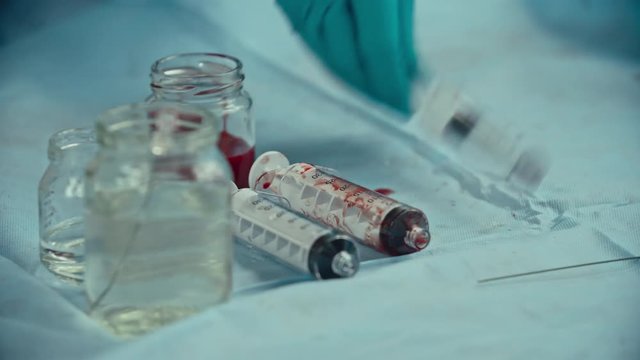 Medical syringes and bottle with water and blood on table during coronary artery bypass graft surgery, close-up shot on Sony NEX 700 + Odyssey 7Q 