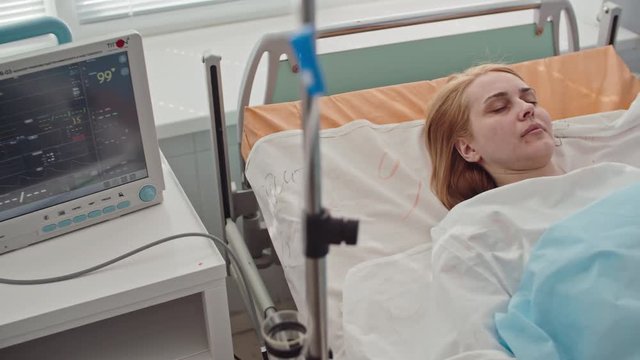 Unconscious female patient attached to heart rate monitor lying in bed in intensive care room, shot on Sony NEX 700 + Odyssey 7Q