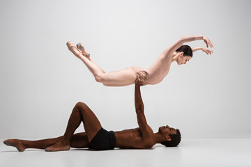 Couple of ballet dancers posing over gray background
