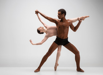Couple of ballet dancers posing over gray background