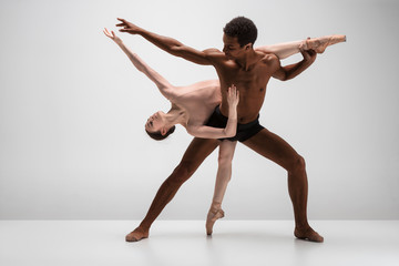 Couple of ballet dancers posing over gray background