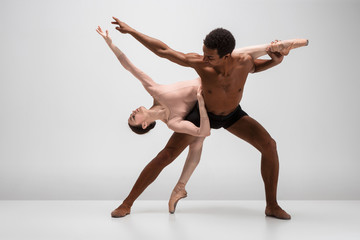 Couple of ballet dancers posing over gray background