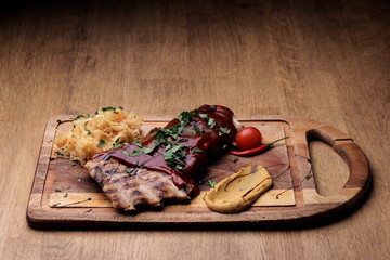 Port steak with red sauce with braised cabbage, fresh cherry tometoes and mustard served on wooden board on rustic wooden counter