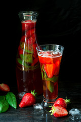 Strawberry lemonade with fresh basil on black wooden background