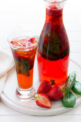 Strawberry lemonade with fresh basil on white wooden background