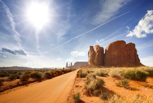 sun shining on a dirt road in monument valley