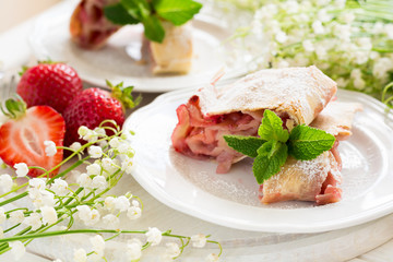 Homemade strudel with strawberries decorated mint leaves  on white wooden background