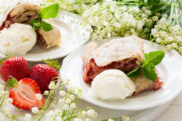 Homemade strudel with strawberries decorated ice-cream and mint leaves  on white wooden background