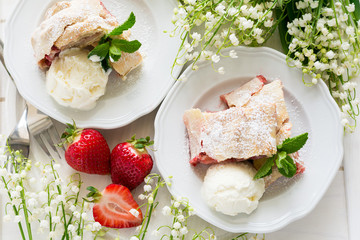 Homemade strudel with strawberries decorated ice-cream and mint leaves  on white wooden background