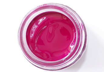 A jar of magenta color gouache on a white background