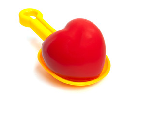 Yellow Spoon beach toys with red heart isolated on white background. Color toys. Beach toys. Isolated toys.Children toys.