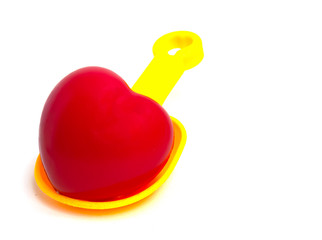 Yellow Spoon beach toys with red heart isolated on white background. Color toys. Beach toys. Isolated toys.Children toys.