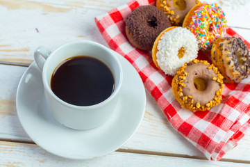 Donuts and coffee on a white wood background.