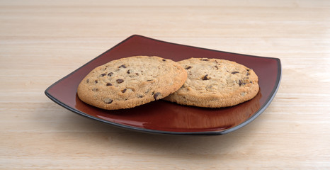 Gluten-free chocolate chip cookies on a plate atop a wood table top