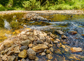 Yellow rocks are seen through the clear water flowing, Khao Sok National Park, Surat Thani Province, Thailand.