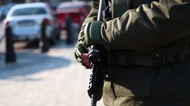 The soldier is on duty in the city with a gun