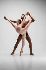 Couple of ballet dancers posing over gray background