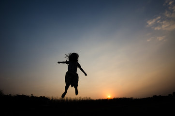 Fototapeta na wymiar Silhouette of a girl gesture happy with the golden light of the sunset,
