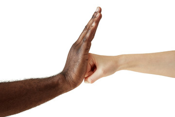 Two people of different races and ethnicities holding hands in handshake expressing friendship, solidarity and cooperation. White Caucasian woman throwing a punch at the open palm of black African man