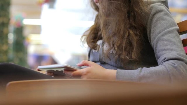 A girl sits on a bench with the tablet