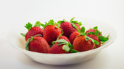Strawberries in the white bowl with white background.