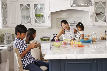 Busy Mother Organizing Children At Breakfast In Kitchen