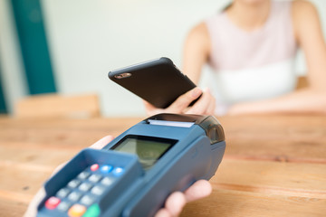 Woman paying with NFC technology on mobile phone