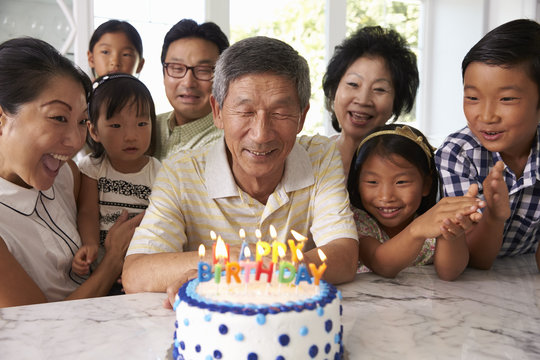 Grandfather Blows Out Candles On Birthday Cake