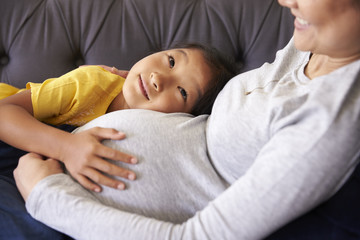 Pregnant Mother Relaxing On Sofa With Daughter