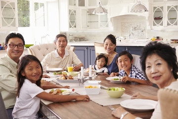 Extended Family Group Eating Meal At Home Together