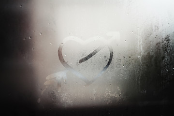 Blurred drops background.Rainy window with fingerprints.Heart wi