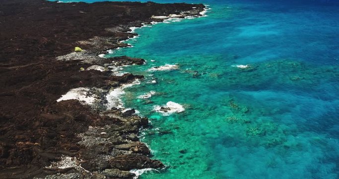 Aerial view over black lava flow and tropical blue ocean coral reef