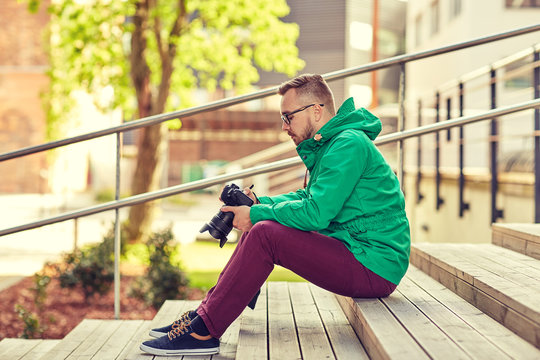 young hipster man with digital camera in city